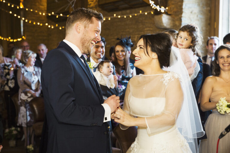 A bride and groom at their wedding ceremony, standing side by side in front of the wedding guests